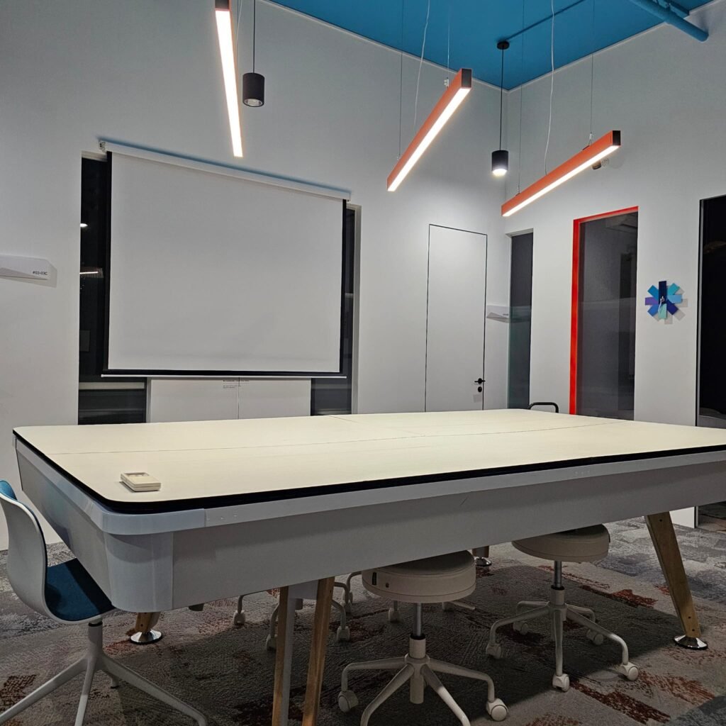 Event space at Dott Co+work Woodlands with projector screen and long tables